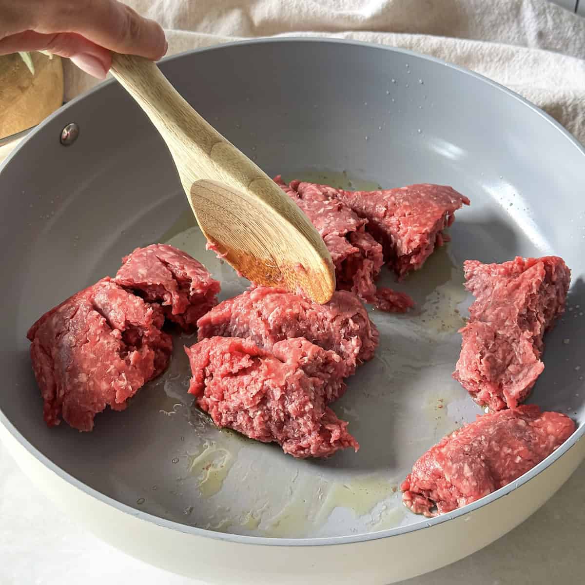wooden spoon breaking apart ground beef.