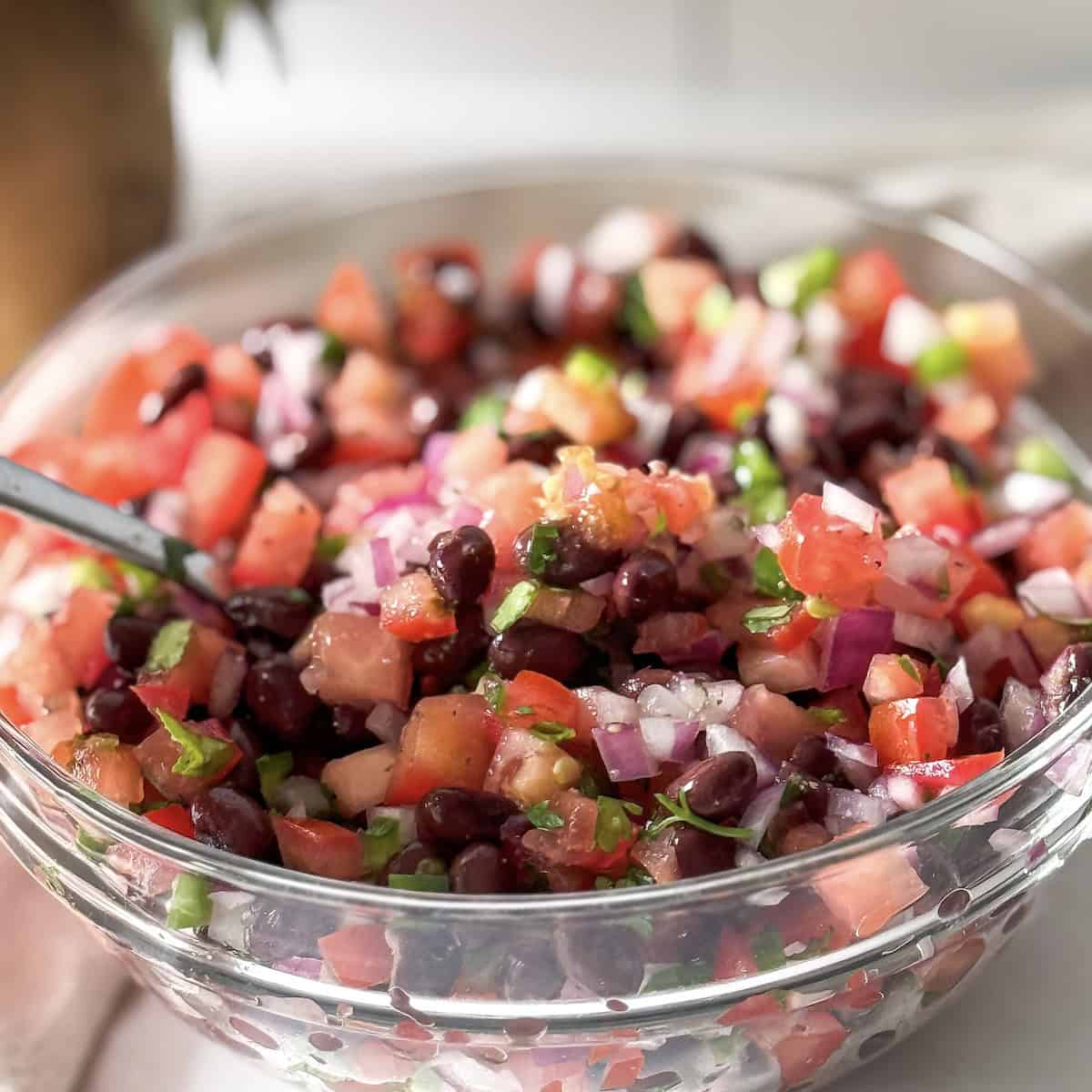 a spoon dishing up a bite of black bean salsa no corn.