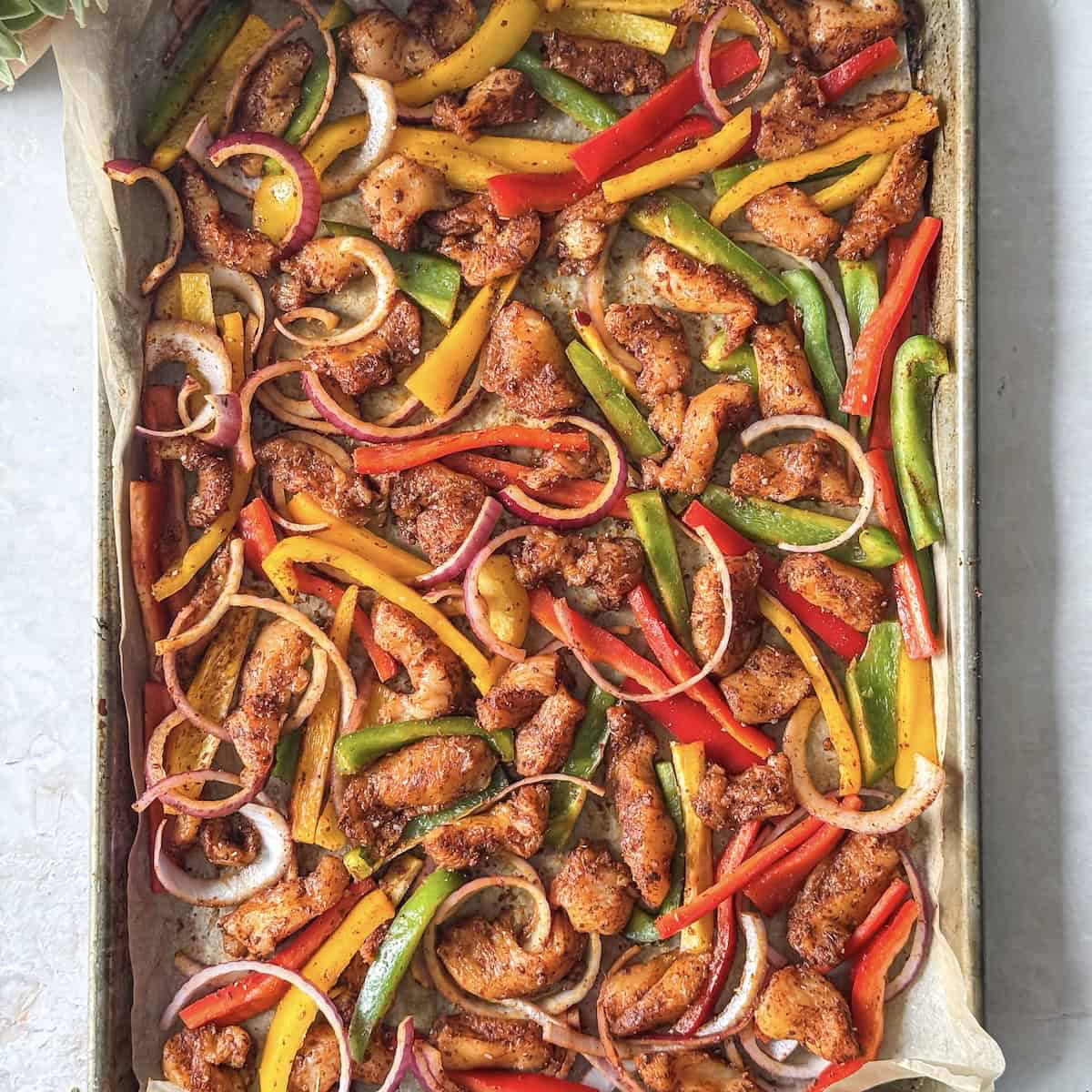 chicken and bell peppers seasoned on a baking sheet overhead view.