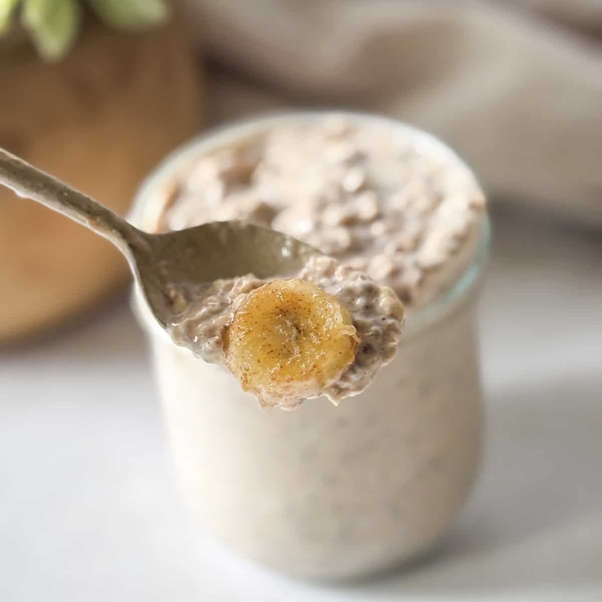 human hand taking a bite of banana cinnamon overnight oatmeal on a spoon.