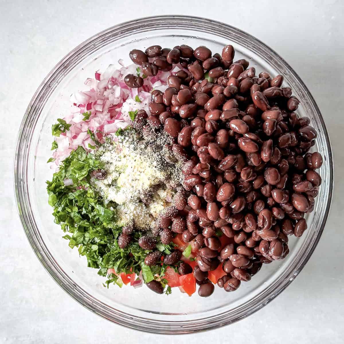 overhead view of ingredients for black bean salsa no corn in a glass bowl.
