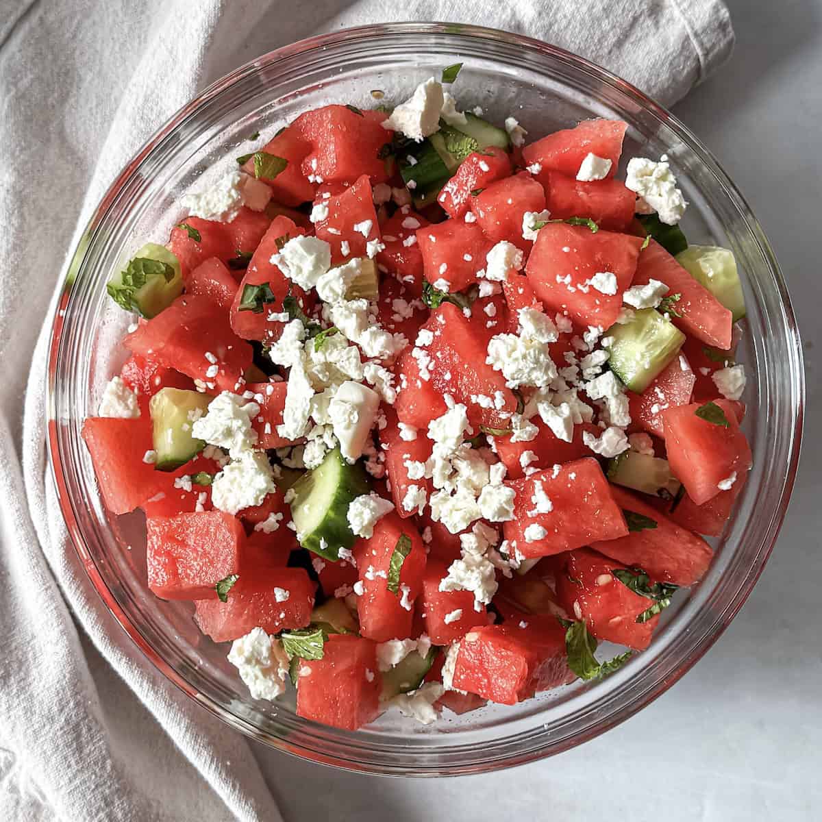 overhead view of watermelon cucumber salad in a glass bowl.