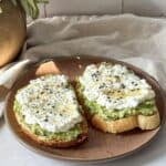 side view of avocado cottage cheese toast on a brown plate.