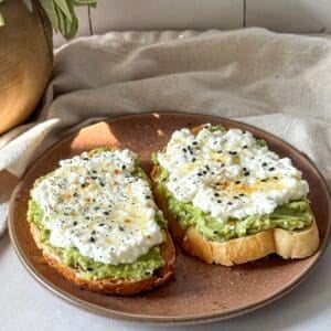 side view of avocado cottage cheese toast on a brown plate.