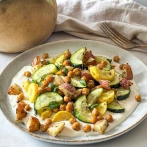 side view of roasted zucchini salad on a plate with a fork.