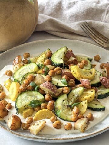 side view of roasted zucchini salad on a plate with a fork.