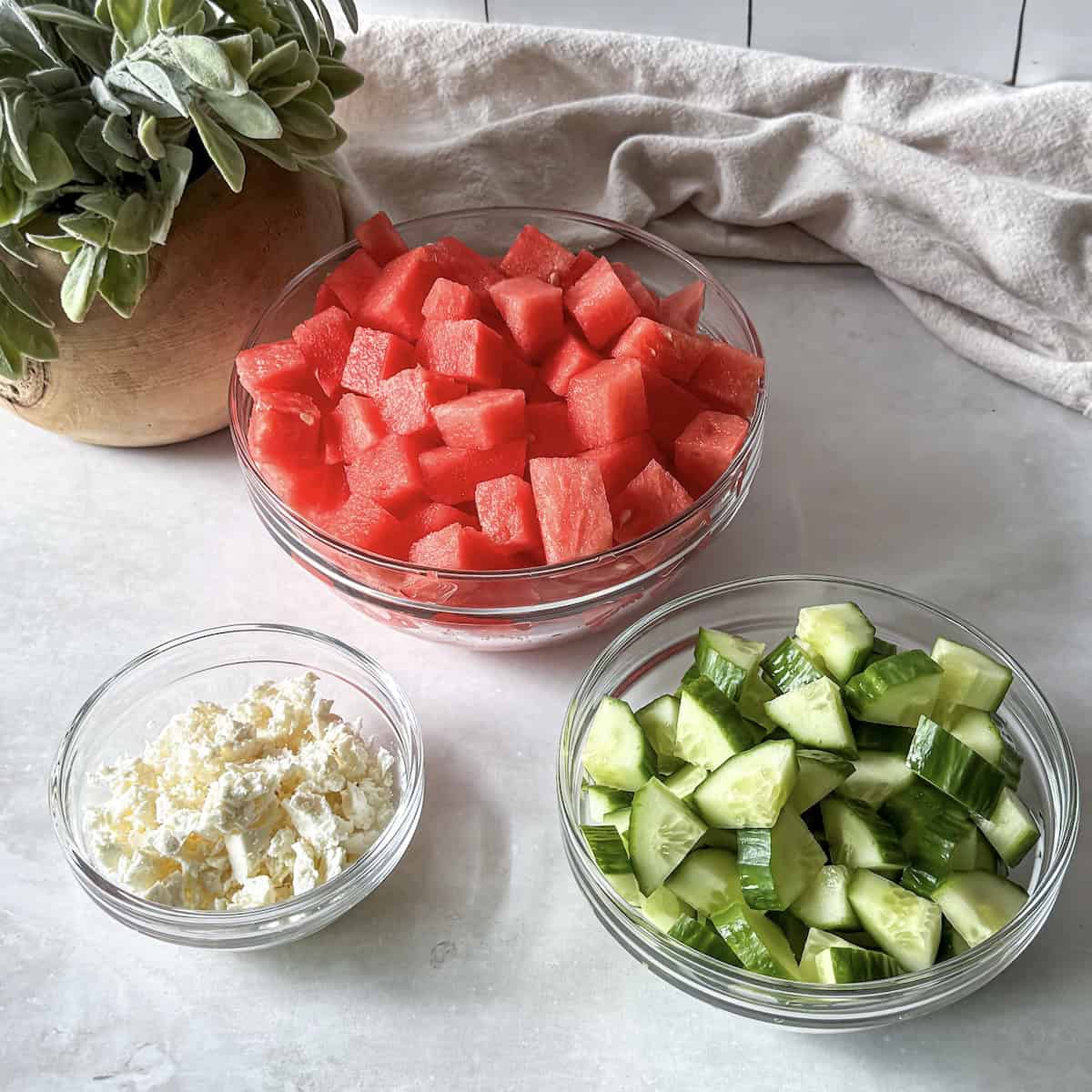 watermelon, cucumber, and feta in small glass bowls.