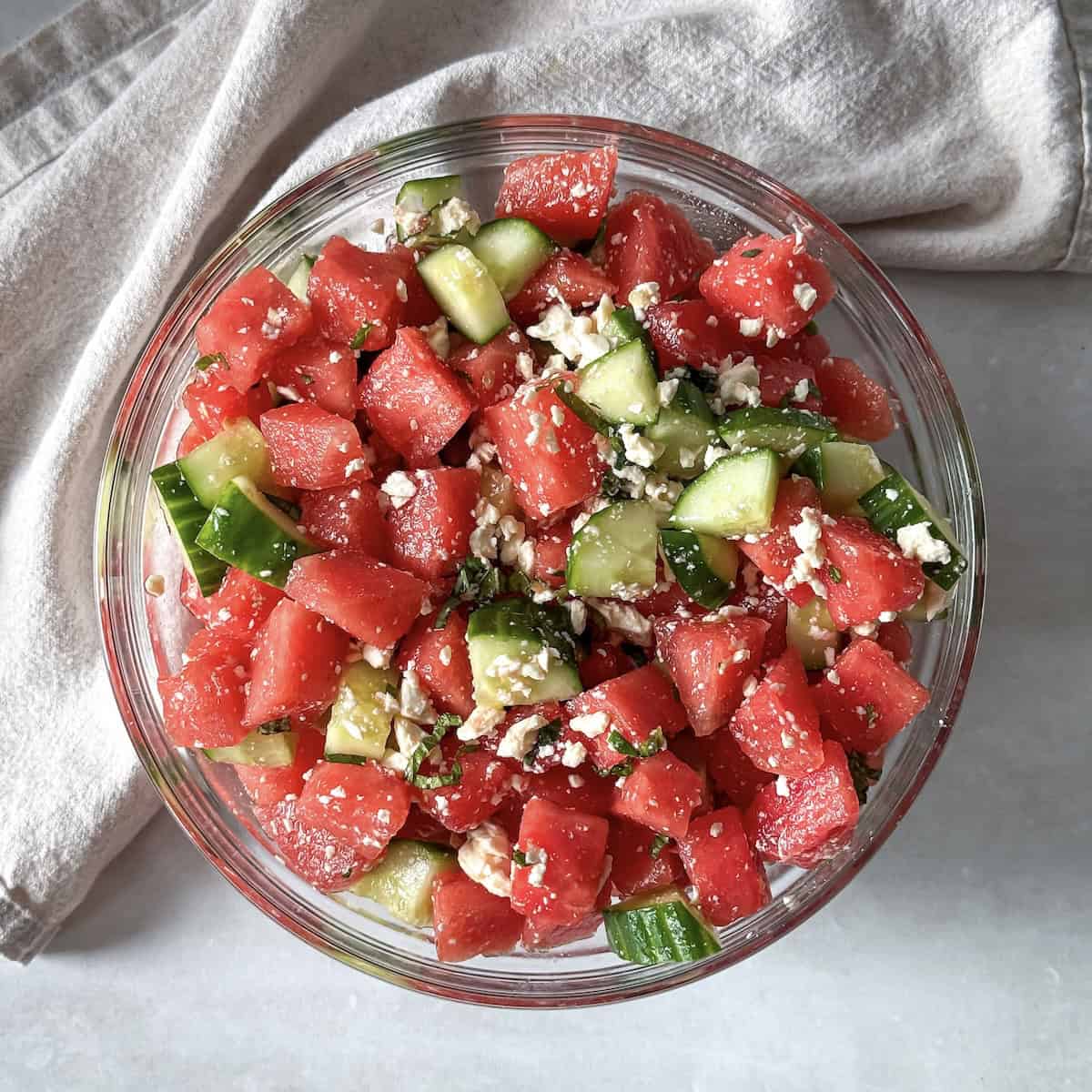watermelon cucumber salad in a glass bowl further away.