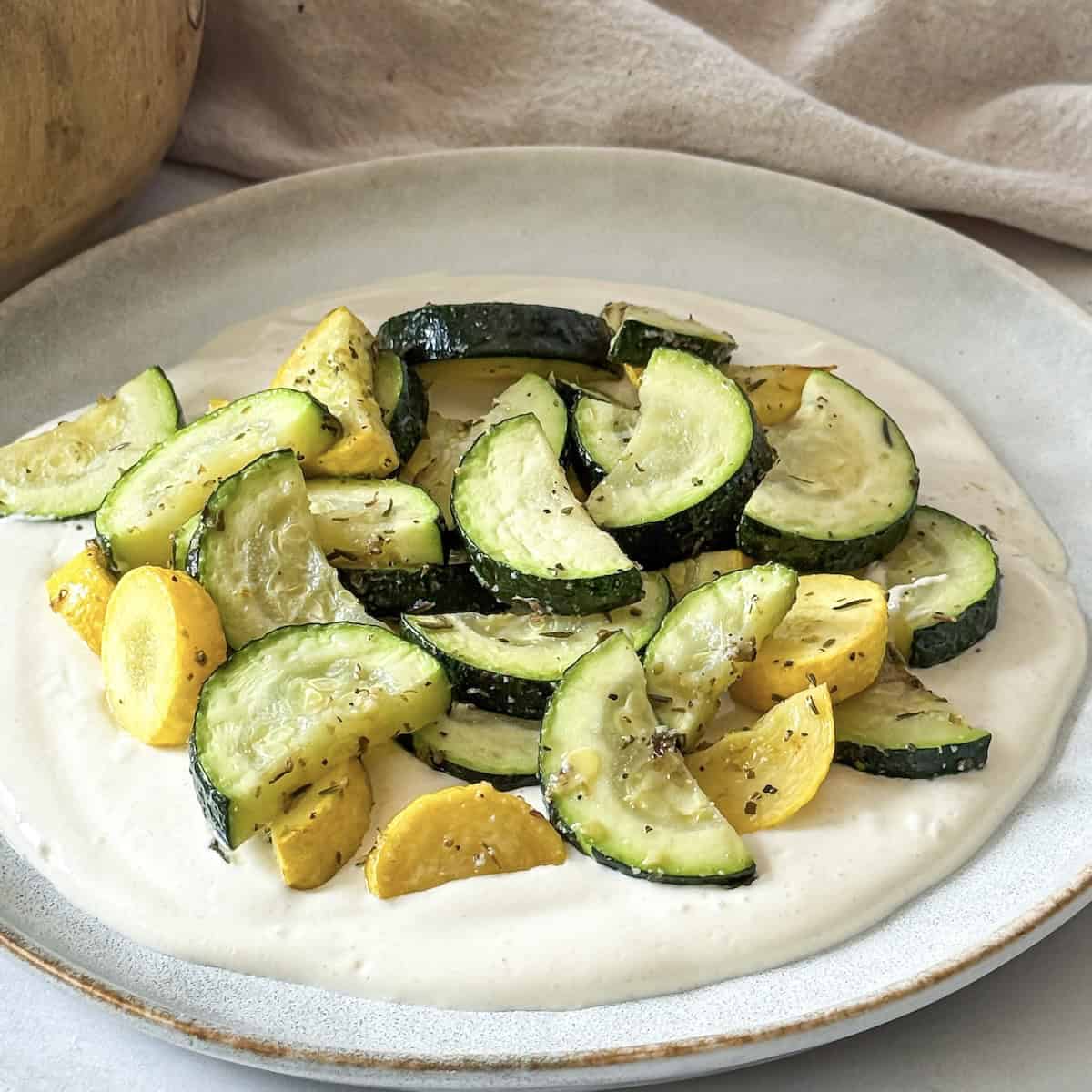 yogurt sauce with zucchini and squash on top.