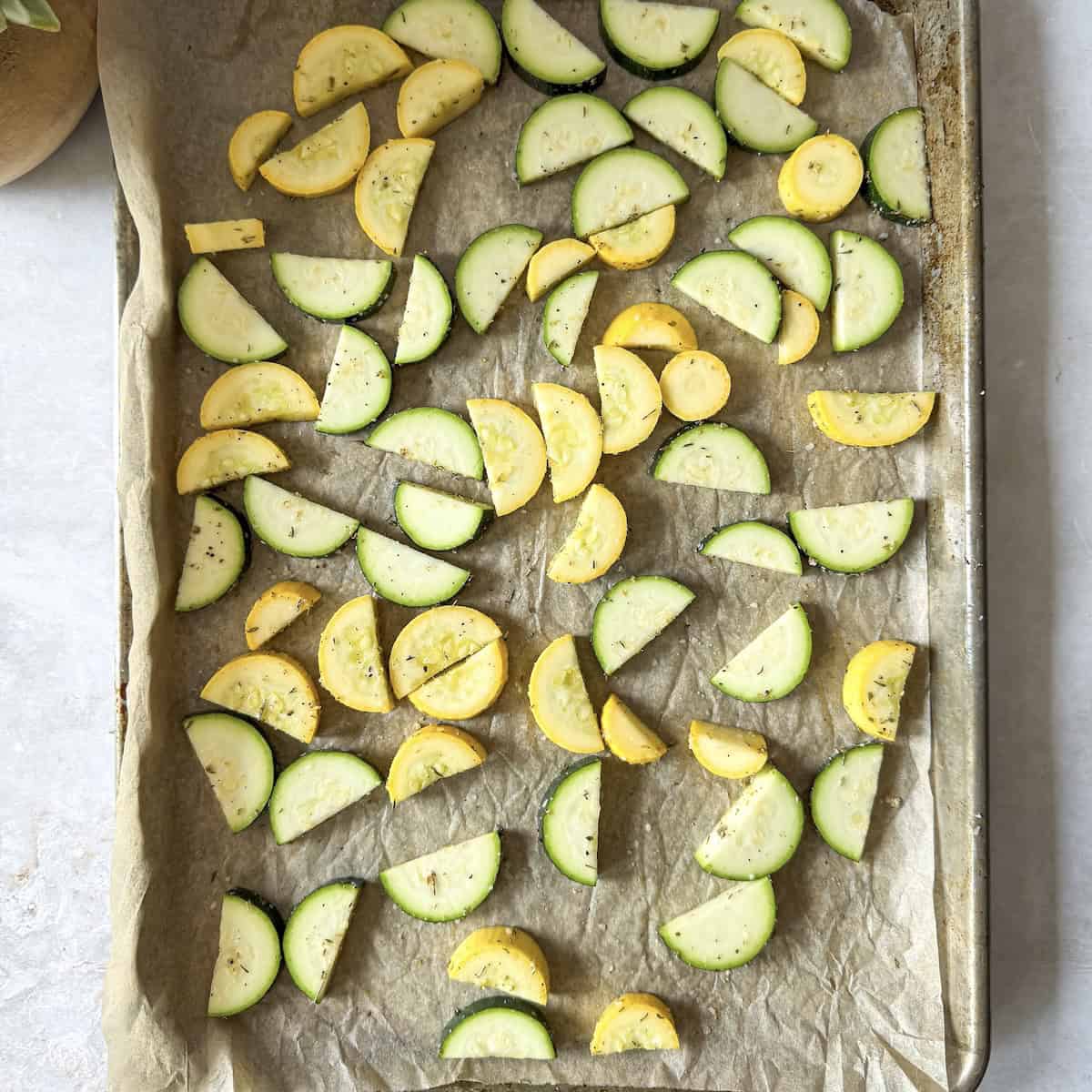 zucchini and summer squash moons on a baking sheet.