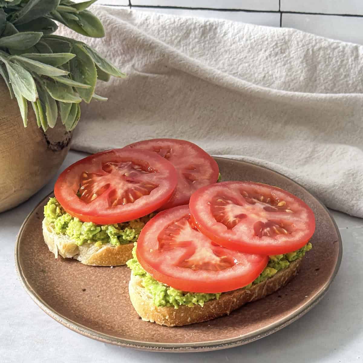 tomato slices added to toast with avocado.