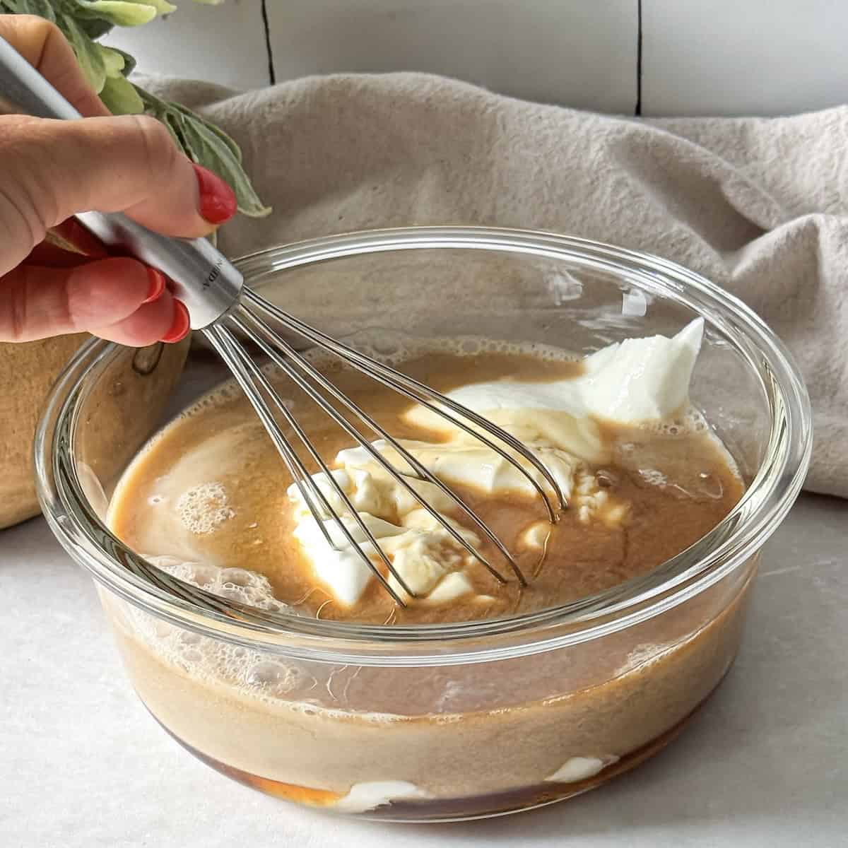 a human hand whisking together greek yogurt, cold brew, and milk.