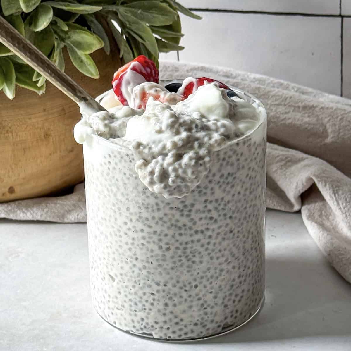 an overflow of chia pudding with yogurt from a glass container.