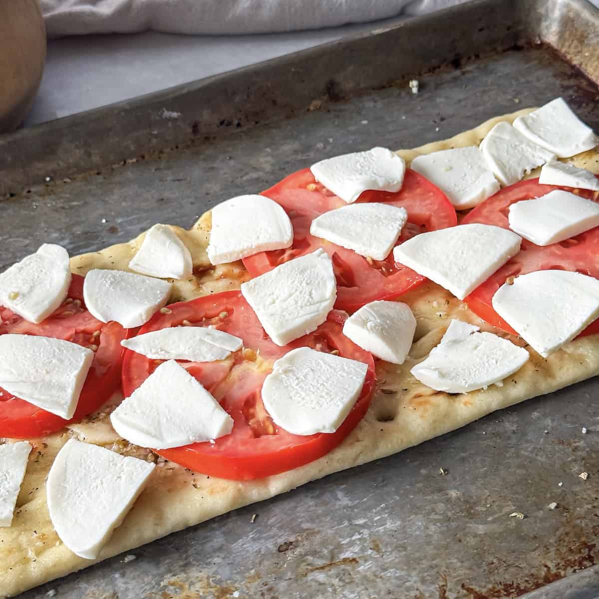 fresh mozzarella on top of tomaotes on flatbread.