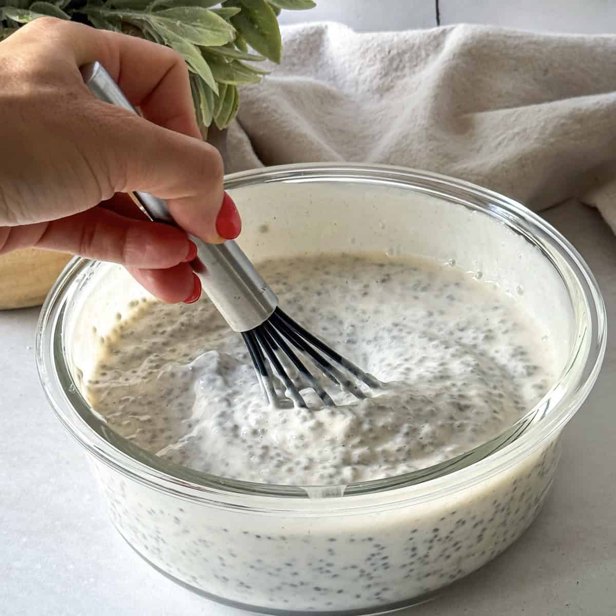 human hand whisking chia pudding.