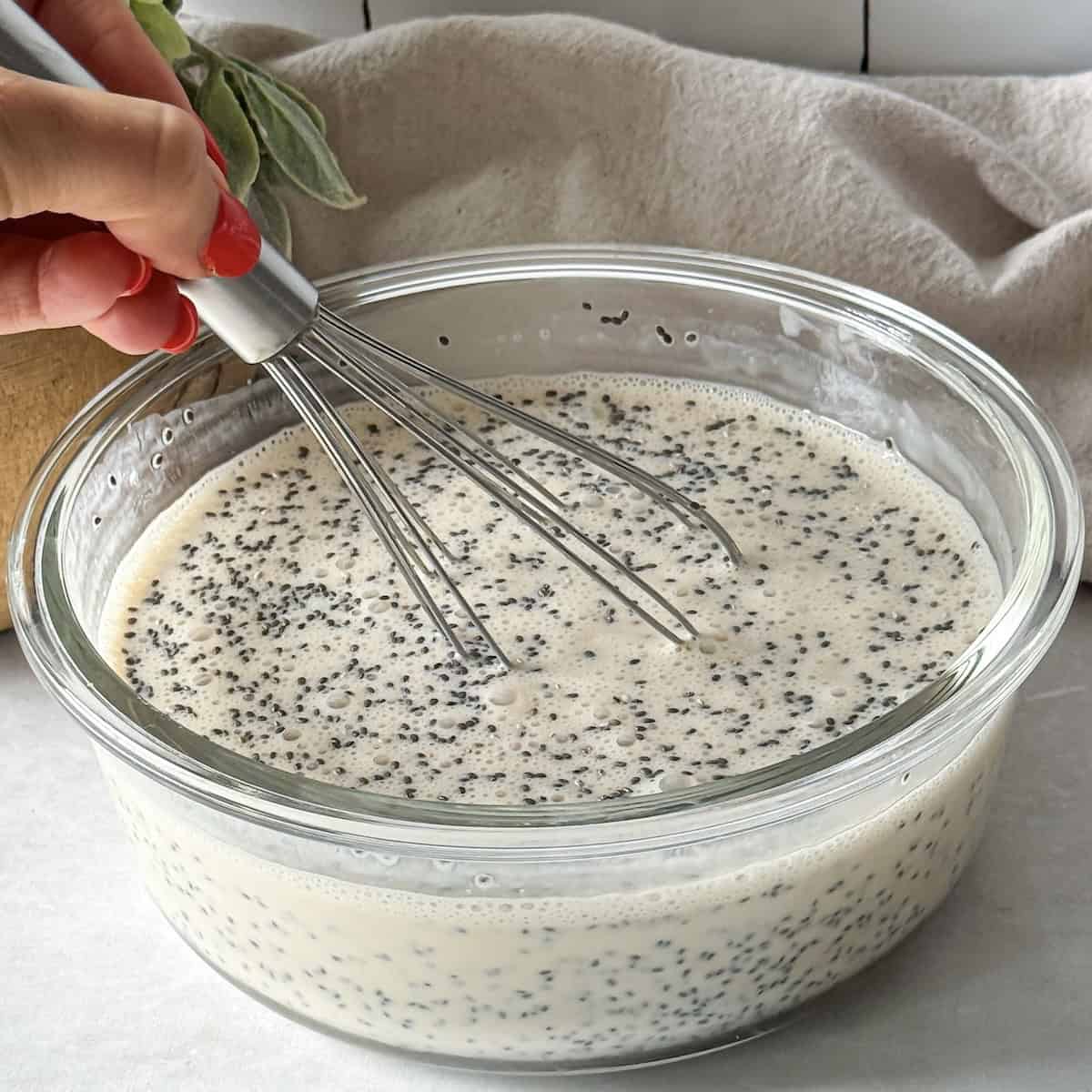 human hand whisking chia seeds into coffee chia pudding.
