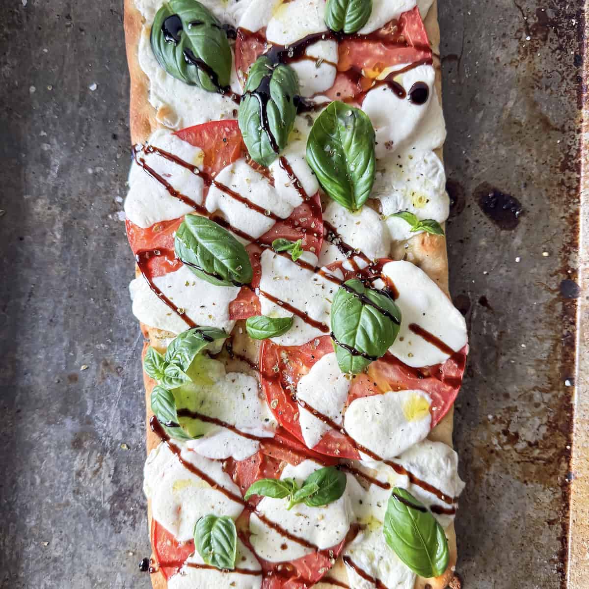 margherita flatbread pizza on a baking sheet overhead.