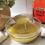 side view of honey lemon dressing with a spoon.
