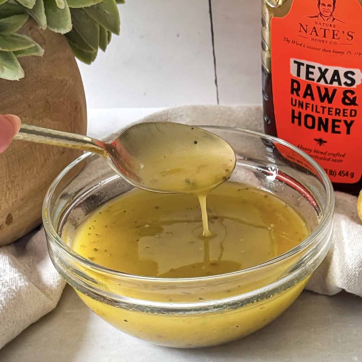 side view of honey lemon dressing with a spoon.