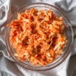 apple carrot salad with greek yogurt dressing in a bowl overhead view.