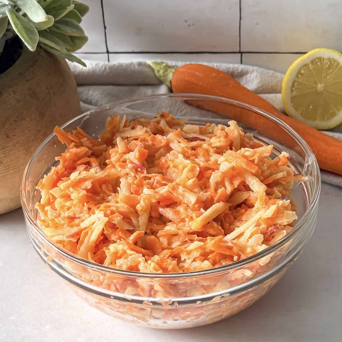 apple carrot salad with greek yogurt dressing in a bowl side view.