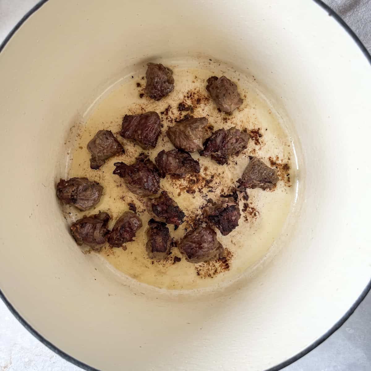 browned beef in the bottom of a pot.