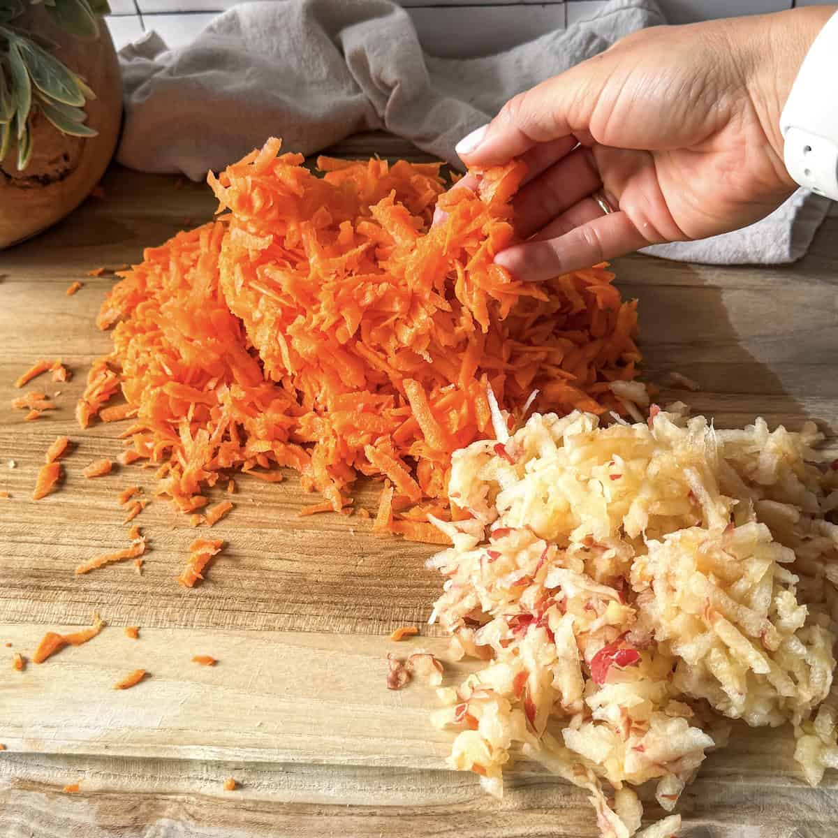 grated carrots and apples on a cutting board.