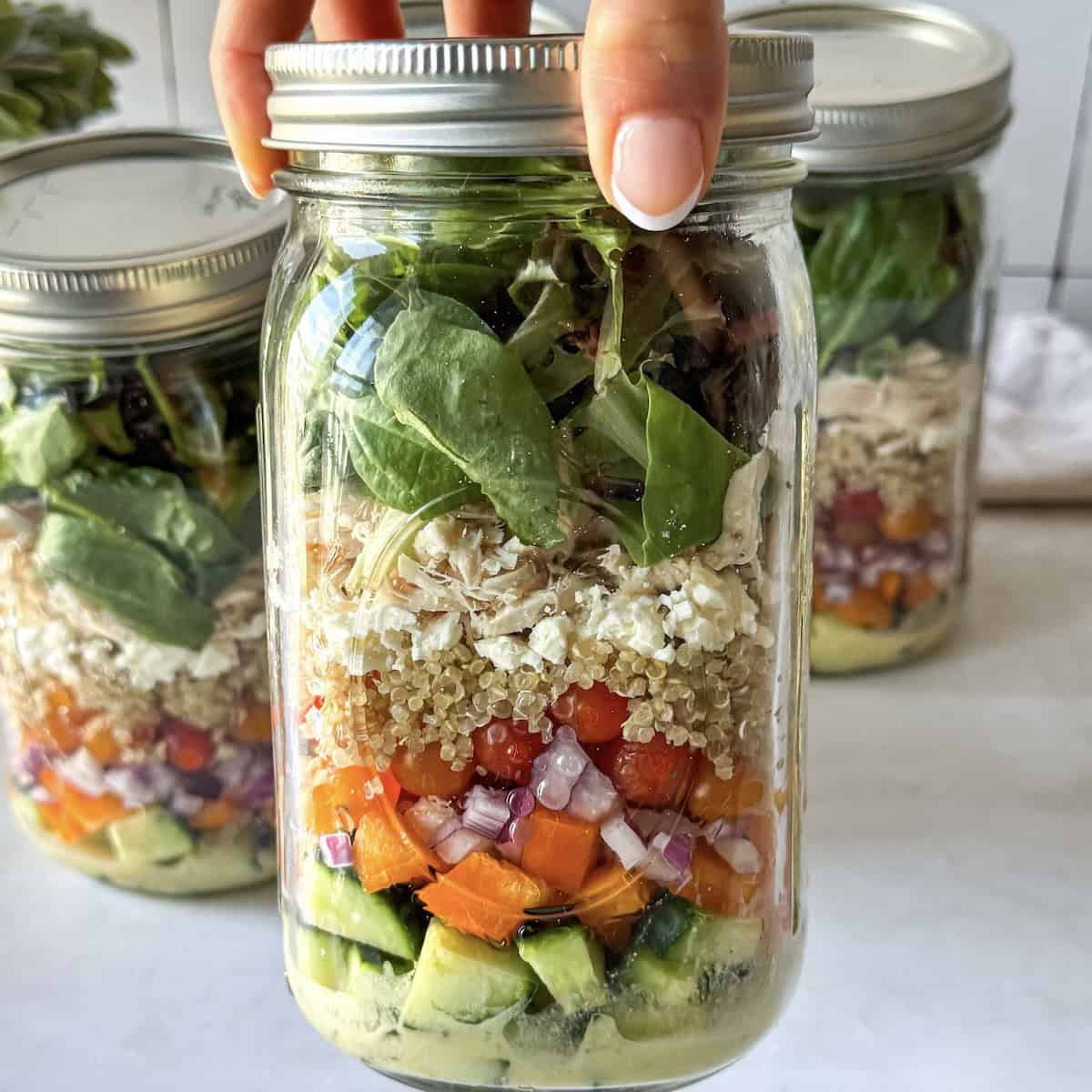 human hand holding a mediterranean salad jar 2