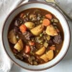 overhead view of beef stew with potatoes and carrots in a bowl.