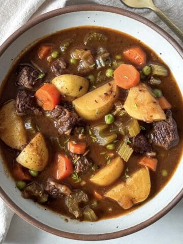 overhead view of beef stew with potatoes and carrots in a bowl.