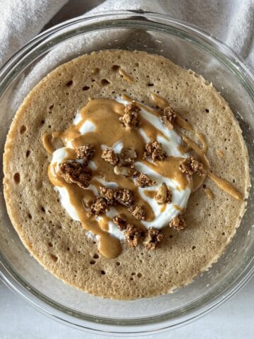 protein pancake bowl with greek yogurt, granola, and nut butter on top.