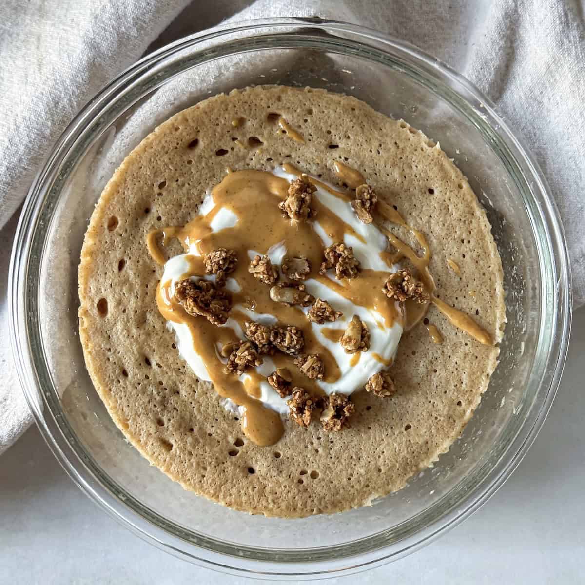 protein pancake bowl with greek yogurt, granola, and nut butter on top.