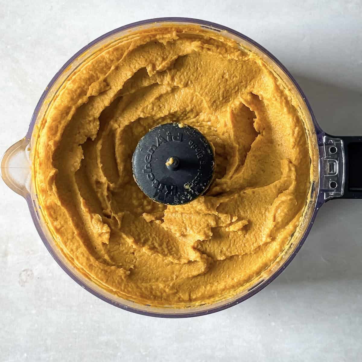 pumpkin hummus in a food processor, overhead view.