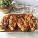 side view thinly sliced baked chicken breast in a baking dish.