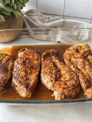 side view thinly sliced baked chicken breast in a baking dish.