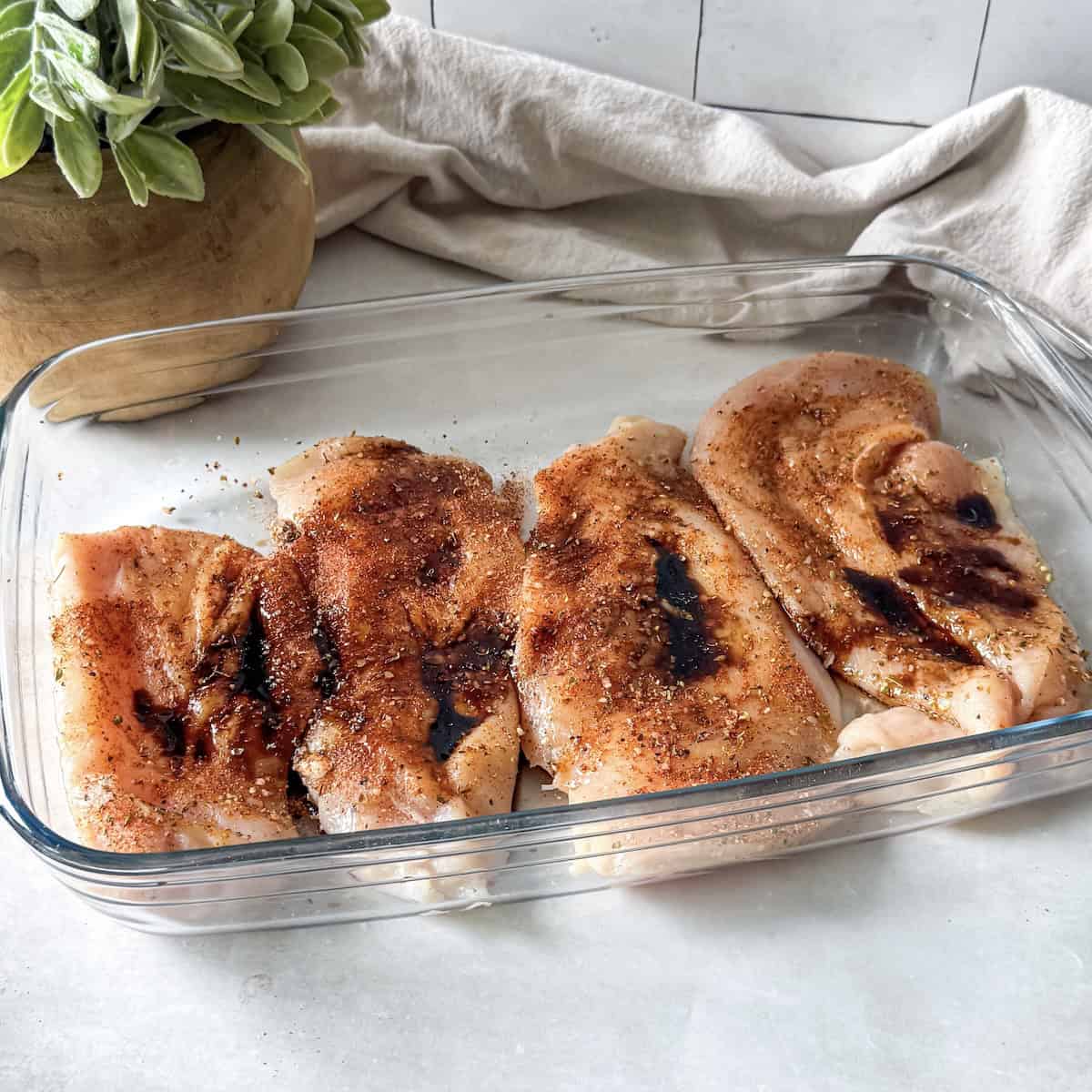thinly sliced chicken breasts in a glass baking dish.