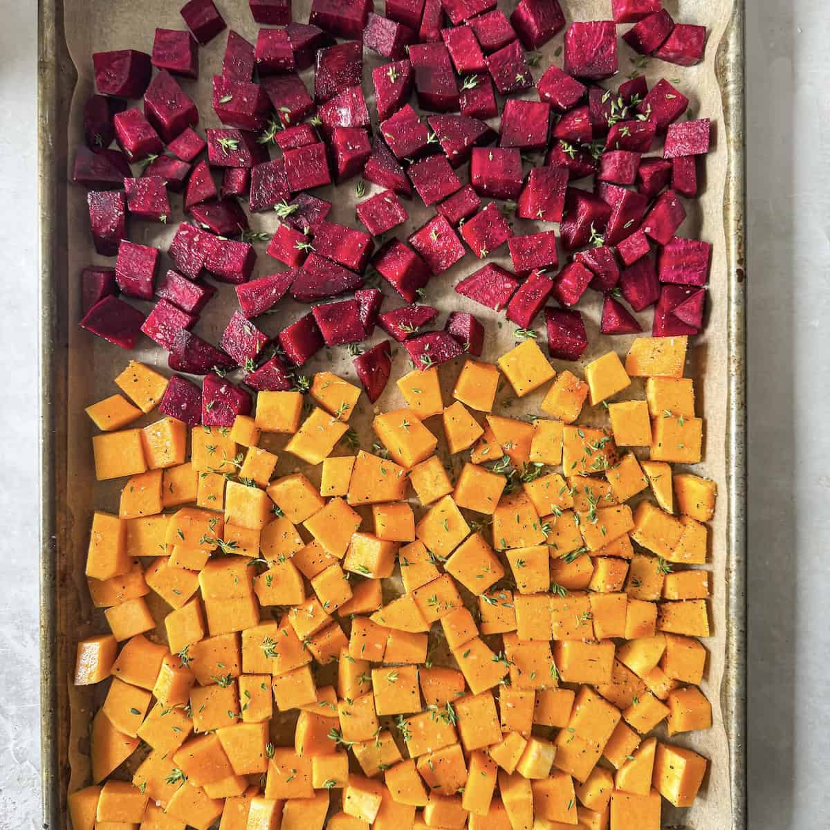 overhead view of beets and butternut squash cubes on a baking sheet.