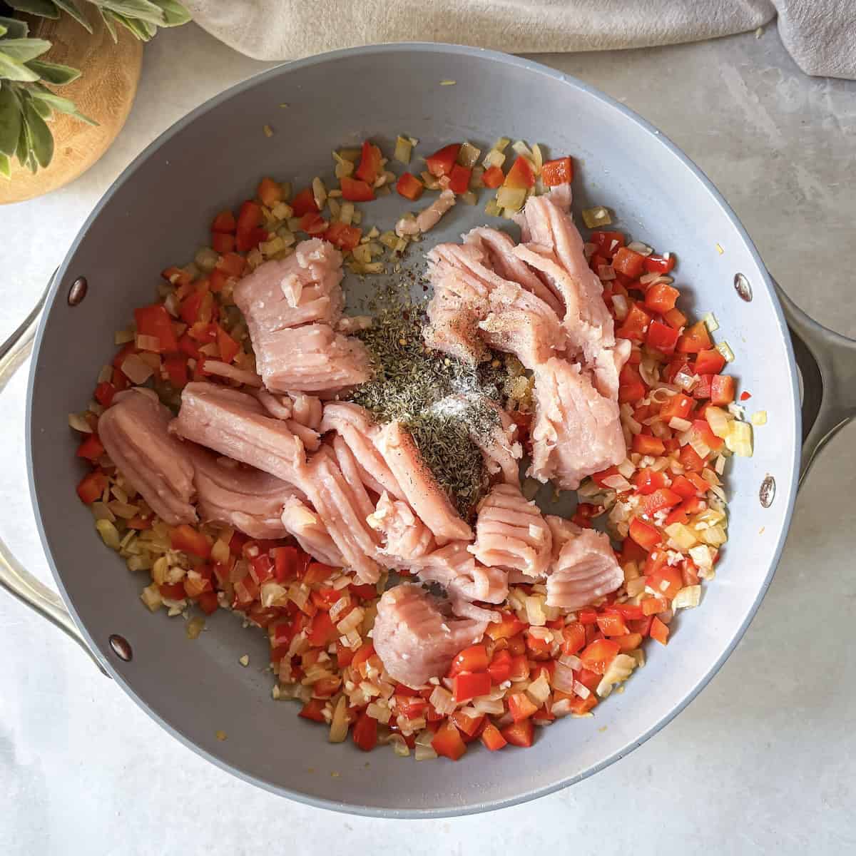 ground turkey in a skillet with bell pepper, onion, and seasonings.