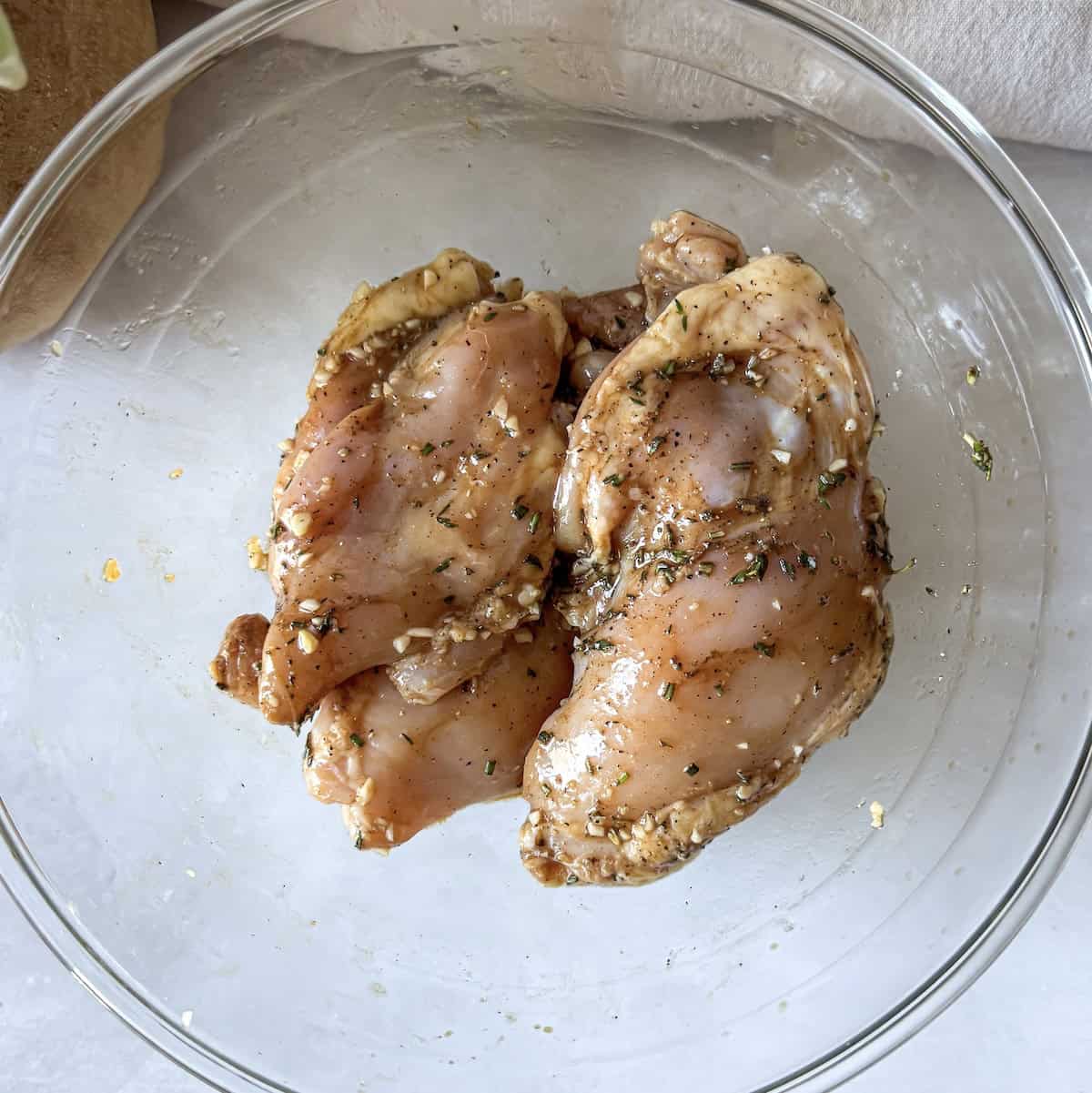 marinated chicken thighs in a glass bowl.