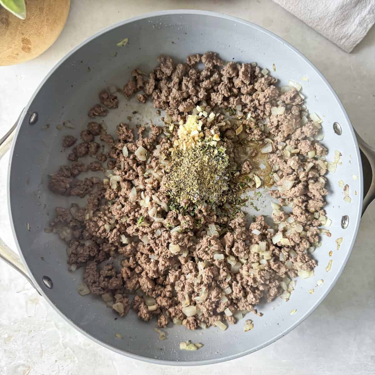 overhead view of thyme, garlic, salt and pepper added to skillet.