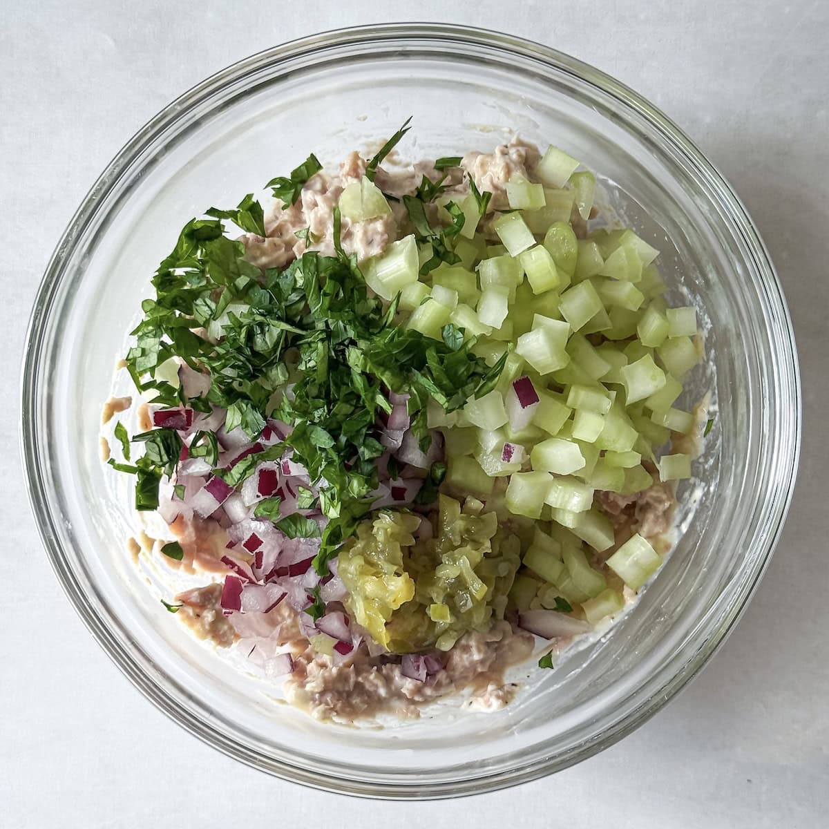 overhead view of veggies added to tuna salad.