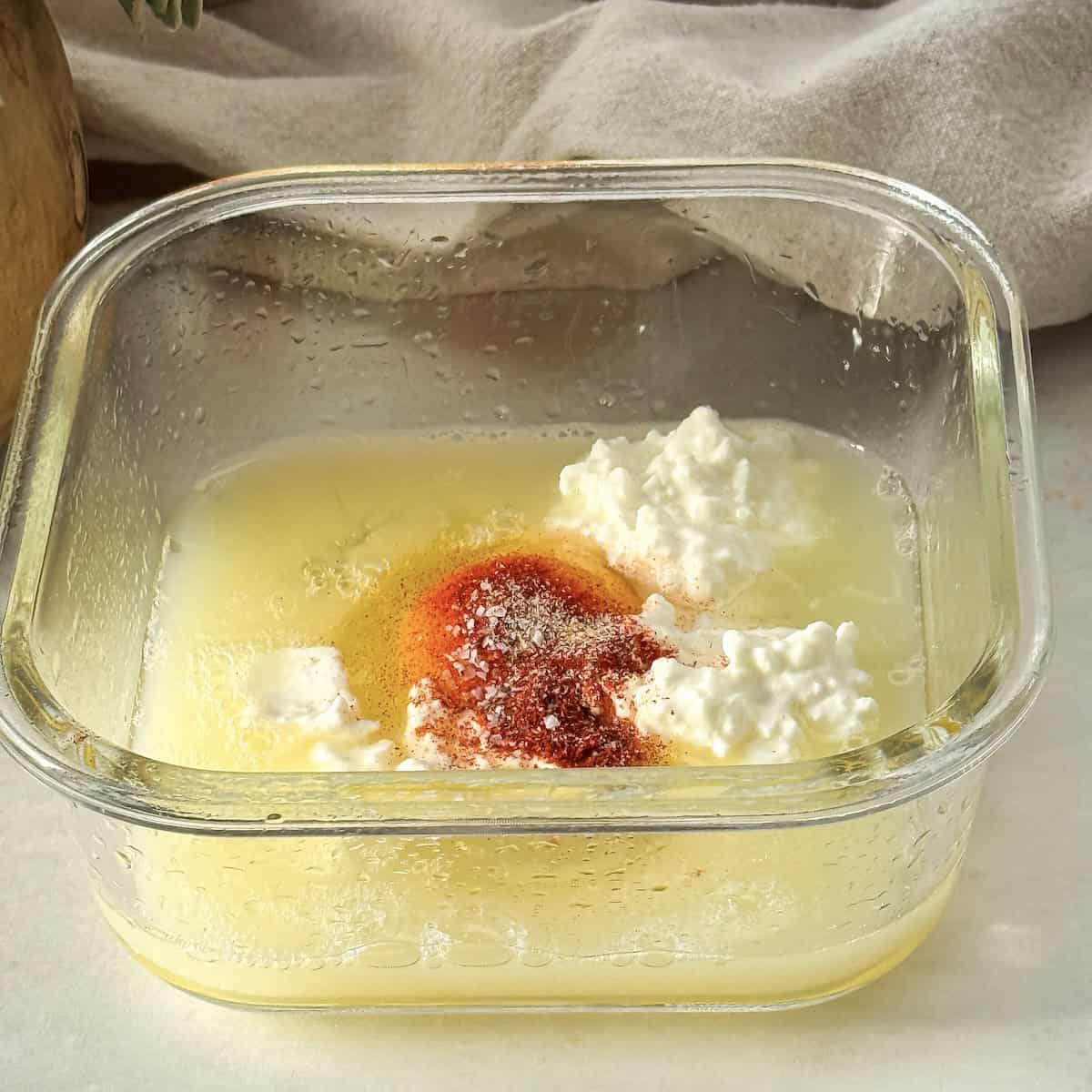 side view of glass container with eggs, egg whites, seasonings, and cottage cheese.