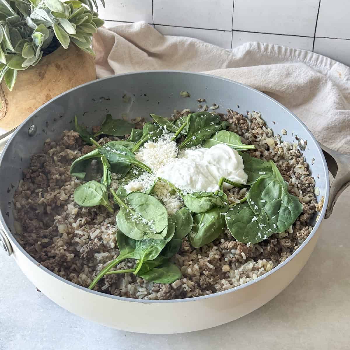 spinach, cheese, and yogurt added to skillet with ground beef and rice.
