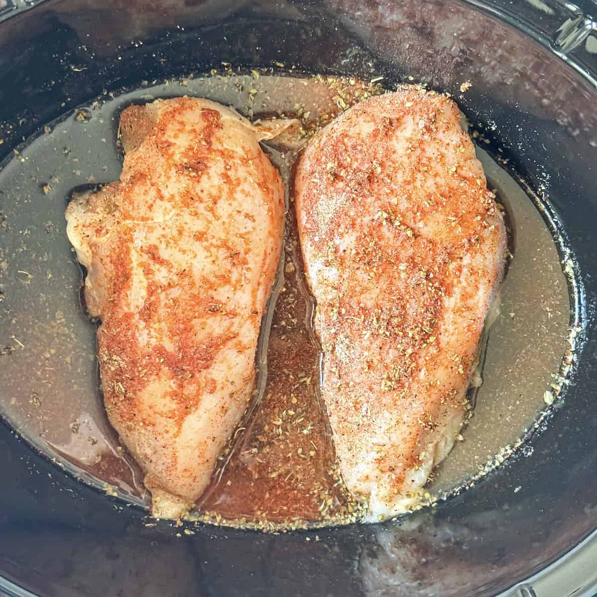 overhead view of seasoned chicken in a crockpot.
