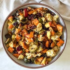 overhead view roasted brussels sprouts and sweet potatoes with cranberries and pecans in a bowl.