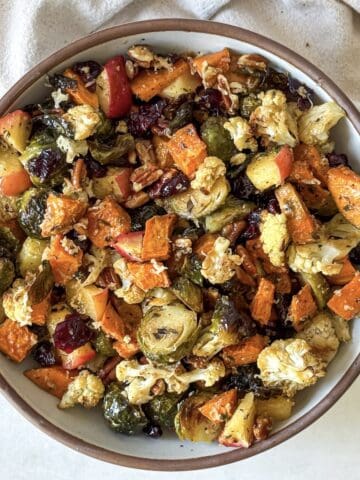 overhead view roasted brussels sprouts and sweet potatoes with cranberries and pecans in a bowl.