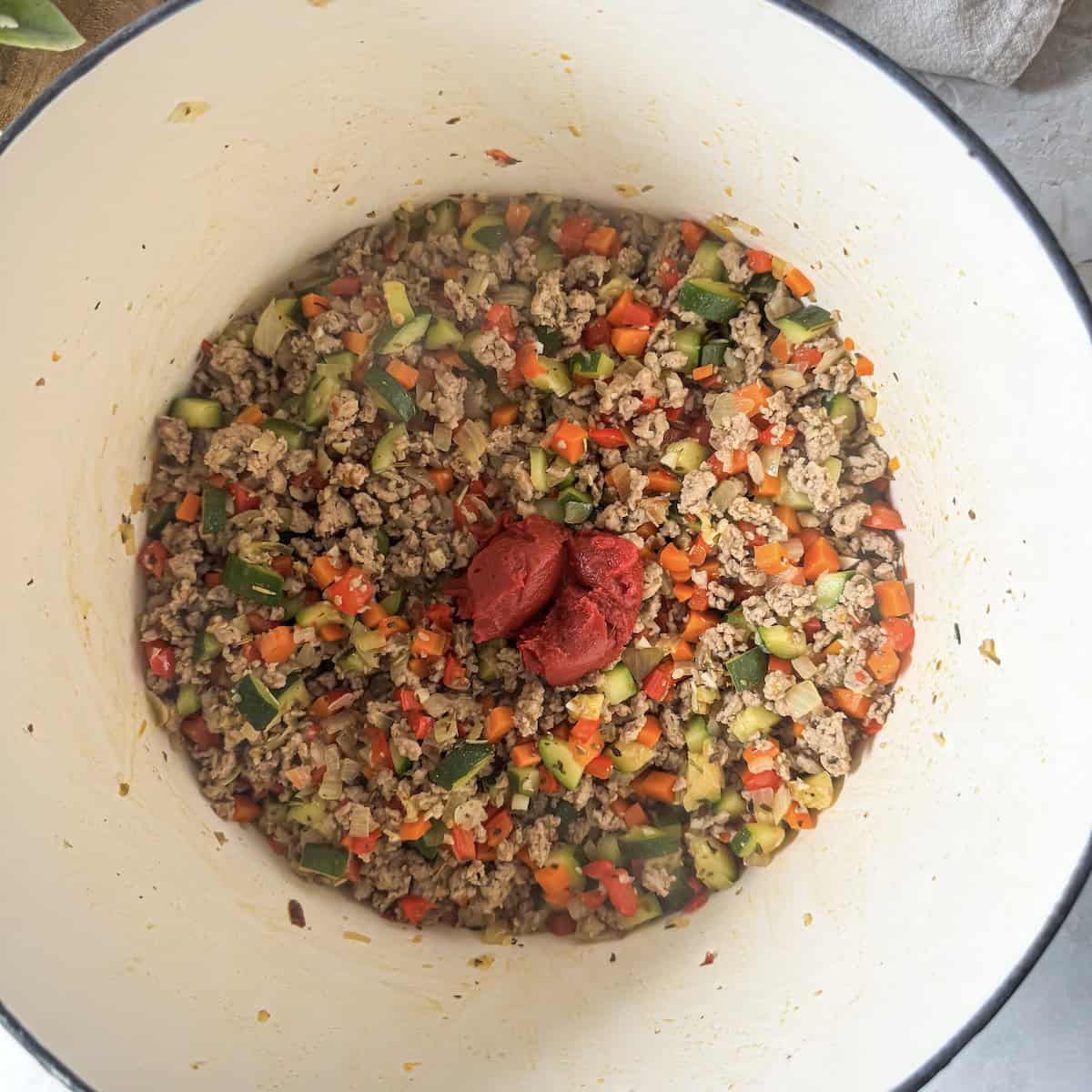 tomato paste added to ground turkey and veggies in a pot.