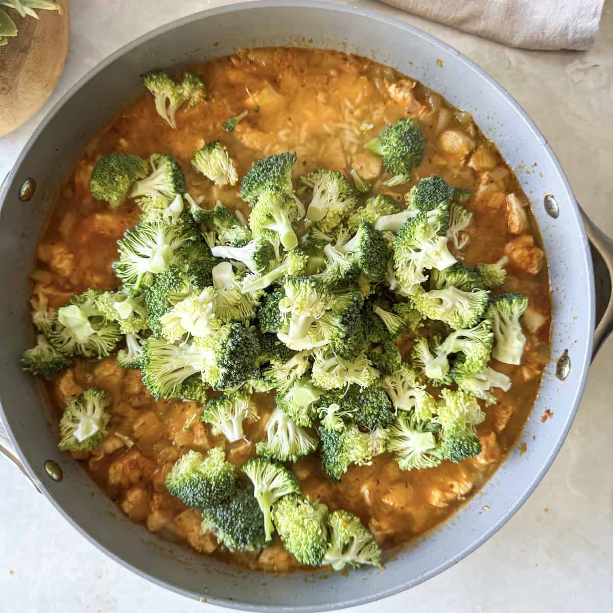 overhead view of broccoli added to skillet dinner.