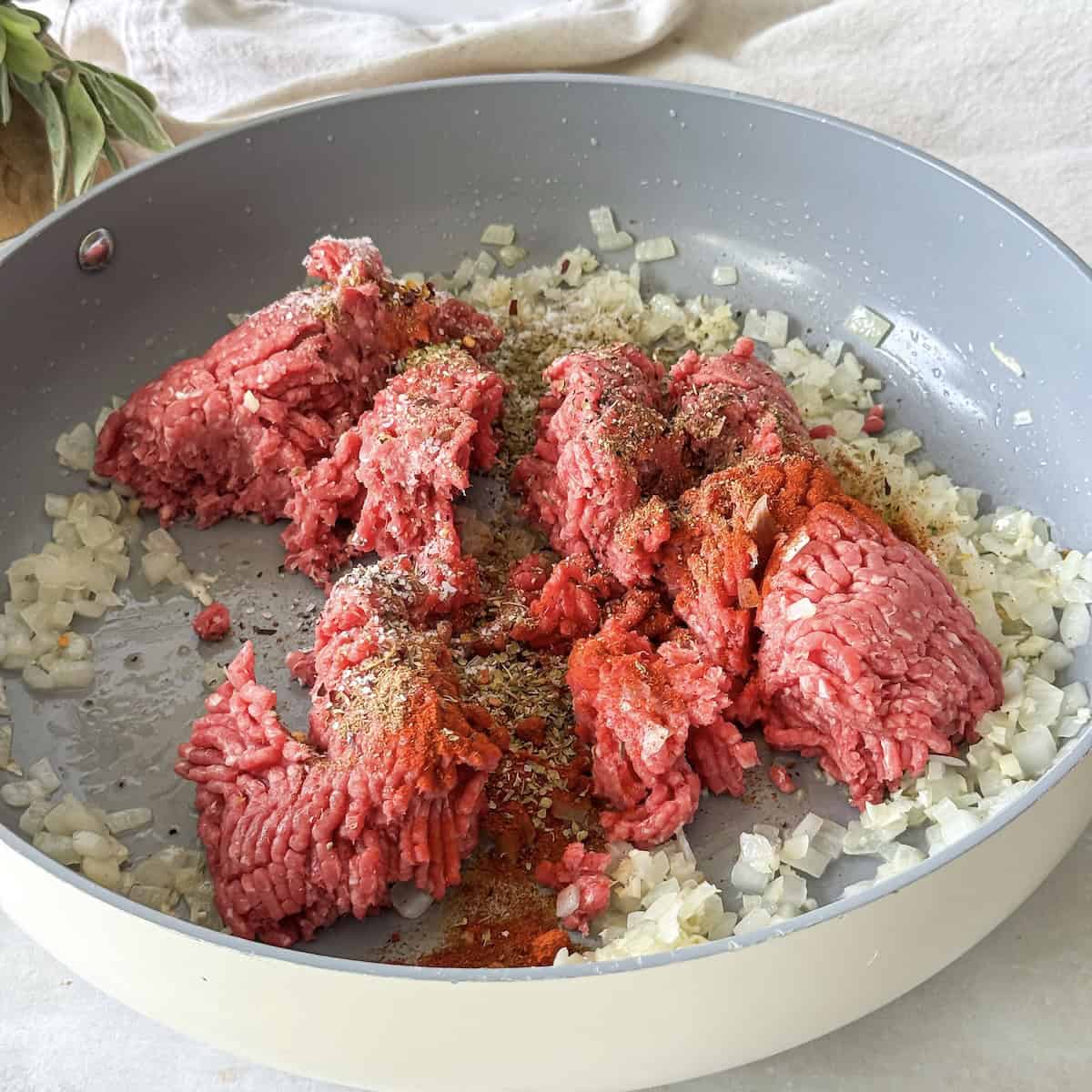 beef and seasonings in a skillet with onions.