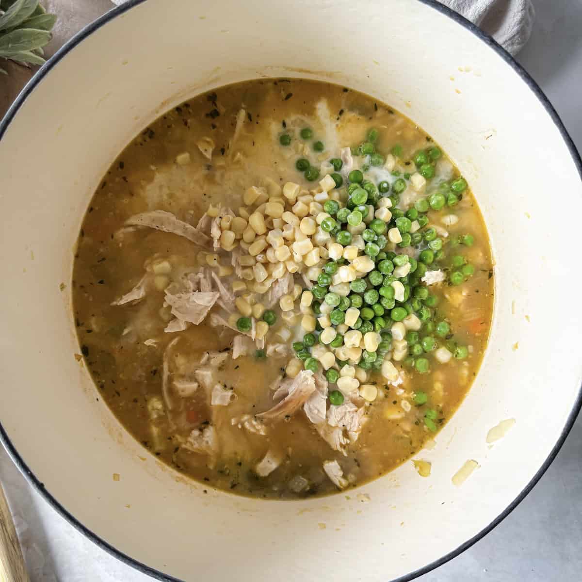 chicken, corn, peas added to a dutch oven.